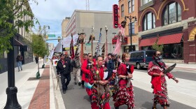 Women in red traditional skirts lead a march down a downtown street in Grand Rapids. 