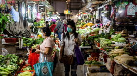 A woman walks through the wet markets wearing a protective face mask in Hong Kong.
