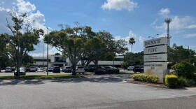 Exterior shot of a medical building parking lot with trees and a clear blue sky.