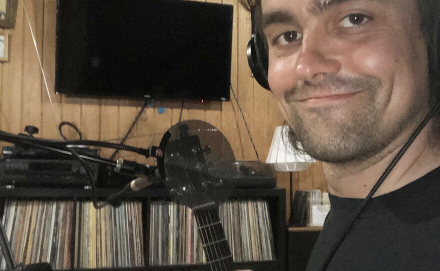 Man smiling while taking a selfie while wearing headphones.
