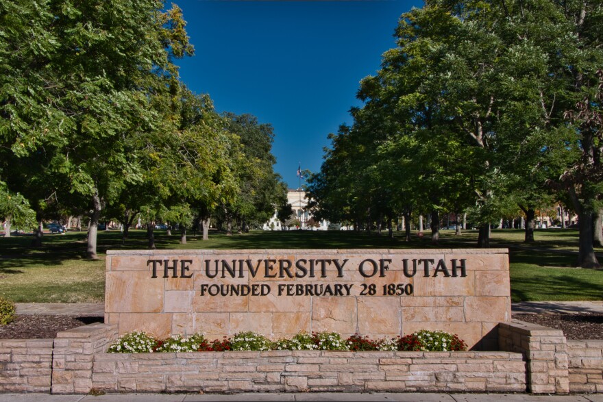 The University of Utah sign in front a tree-filled quad.