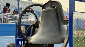 A big iron bell, mounted to a blue metal cart, sits on the track at Walla Walla High School's Blue Devil Stadium.
