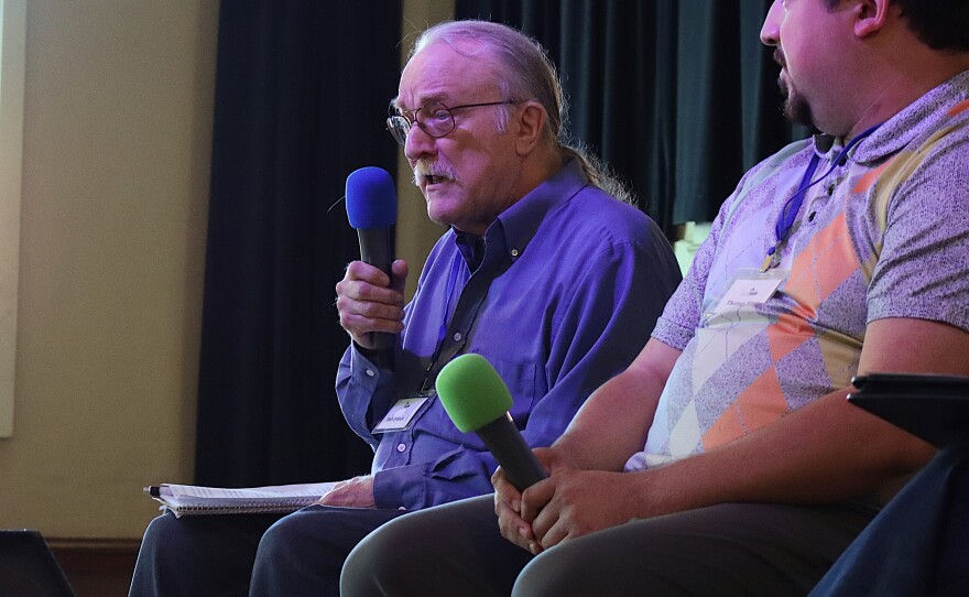 Two people sitting on stage holding microphones.