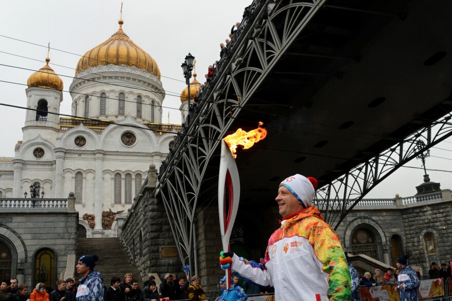 One of the participants of the Sochi 2014 Winter Olympic torch relay runs near the Christ the Savior Cathedral in Moscow, on Oct. 8. Controversies surrounding costs, security and gay rights swirl around the games, to be held in the Russian Black Sea resort city.