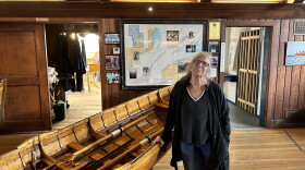 Diane Walton, the president of the Dolphin Club, stands with her hand on one of her club's boats in their clubhouse.