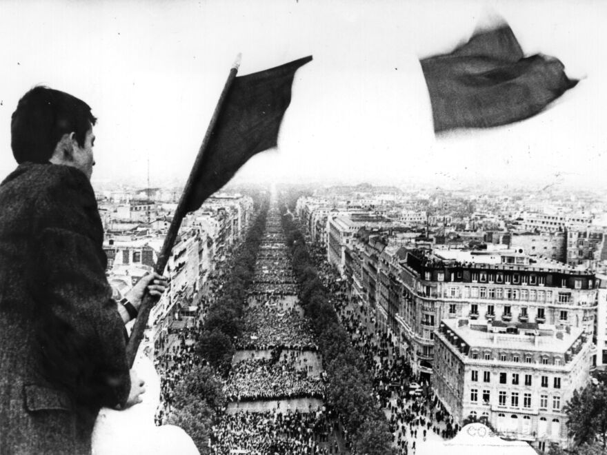 A man flies the French tricolor flag over crowds marching to the Arc de Triomphe during the Paris students' strike.