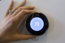 A hand adjusts a digital thermostat