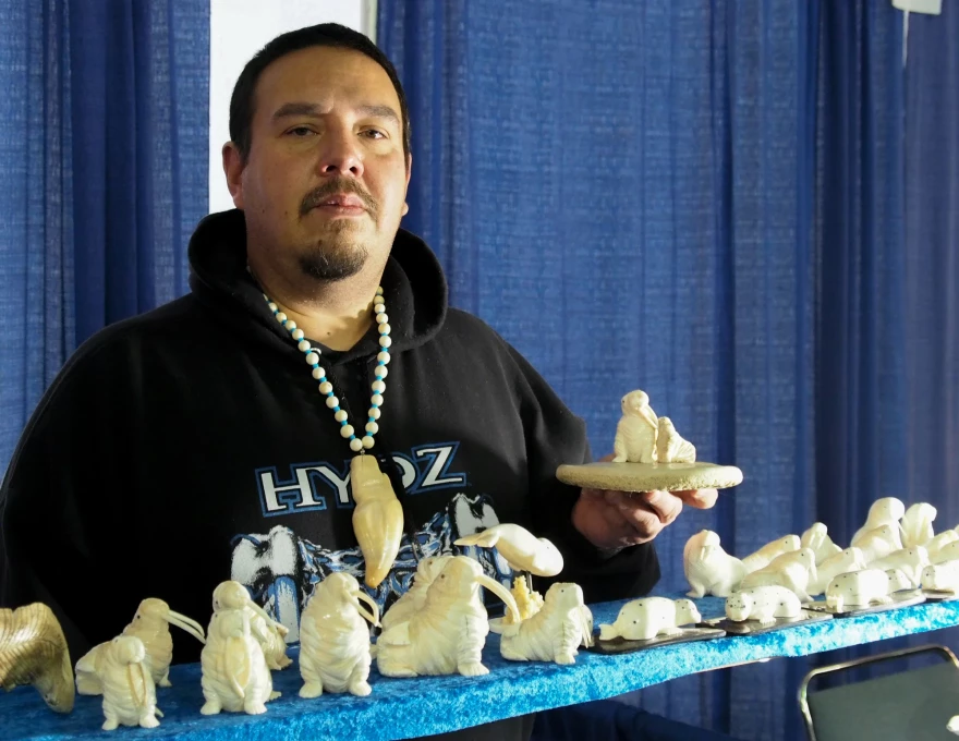 Dennis Pungowiyi shows off one of his favorite carving motifs, a mother walrus with her pup.