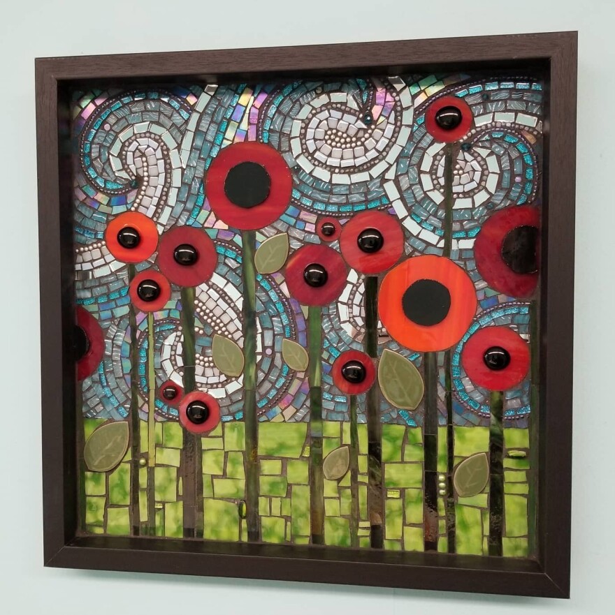 A mosaic art piece of circular flowers and swirling sky behind them. 