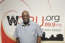 A man poses for a photo in front of a WCBU wall sign
