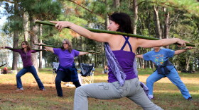 Leela Robinson leads a “Yoga for Gardeners” workshop, showing visitors how to do yoga with bamboo canes that mimic long handled garden tools. Photo by Mariana Riquezes /WUFT News.