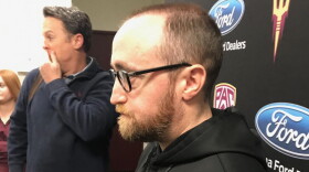 Photo of a man with a beard, glasses and a black hoodie in profile facing left.