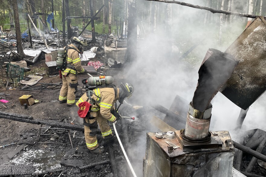 firefighters extinguish flames at an encampment