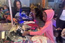 A young girl in a pink hoodie looking at a selection of costumes 