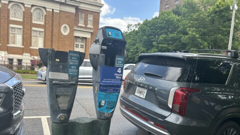 A Close-up of parking meters in downtown Athens. One of them is missing a head, the other has instructions on how to use a new parking app to pay parking fees.