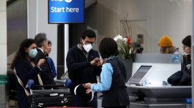 Passengers wear protective masks as they check into an international flight at San Francisco International Airport.
