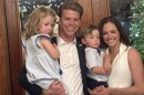 Austin Rogers poses with his wife and two kids, a boy and a girl, in front of a door.