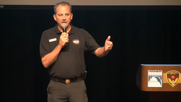Tom Clemo, the incident commander for the California team leading the Spokane wildfire suppression effort, speaks Tuesday night at a Shadle Park High School community meeting.