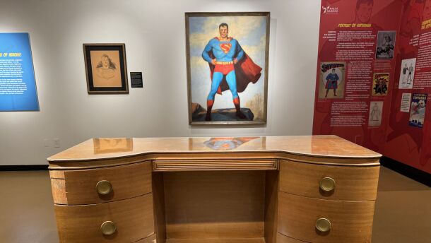 The “Icons in Ink’’ exhibition at the Maltz Museum includes the writing desk of Jerry Siegel, co-creator of Superman along with Joe Shuster, and a 1940s vintage Superman advertising painting.