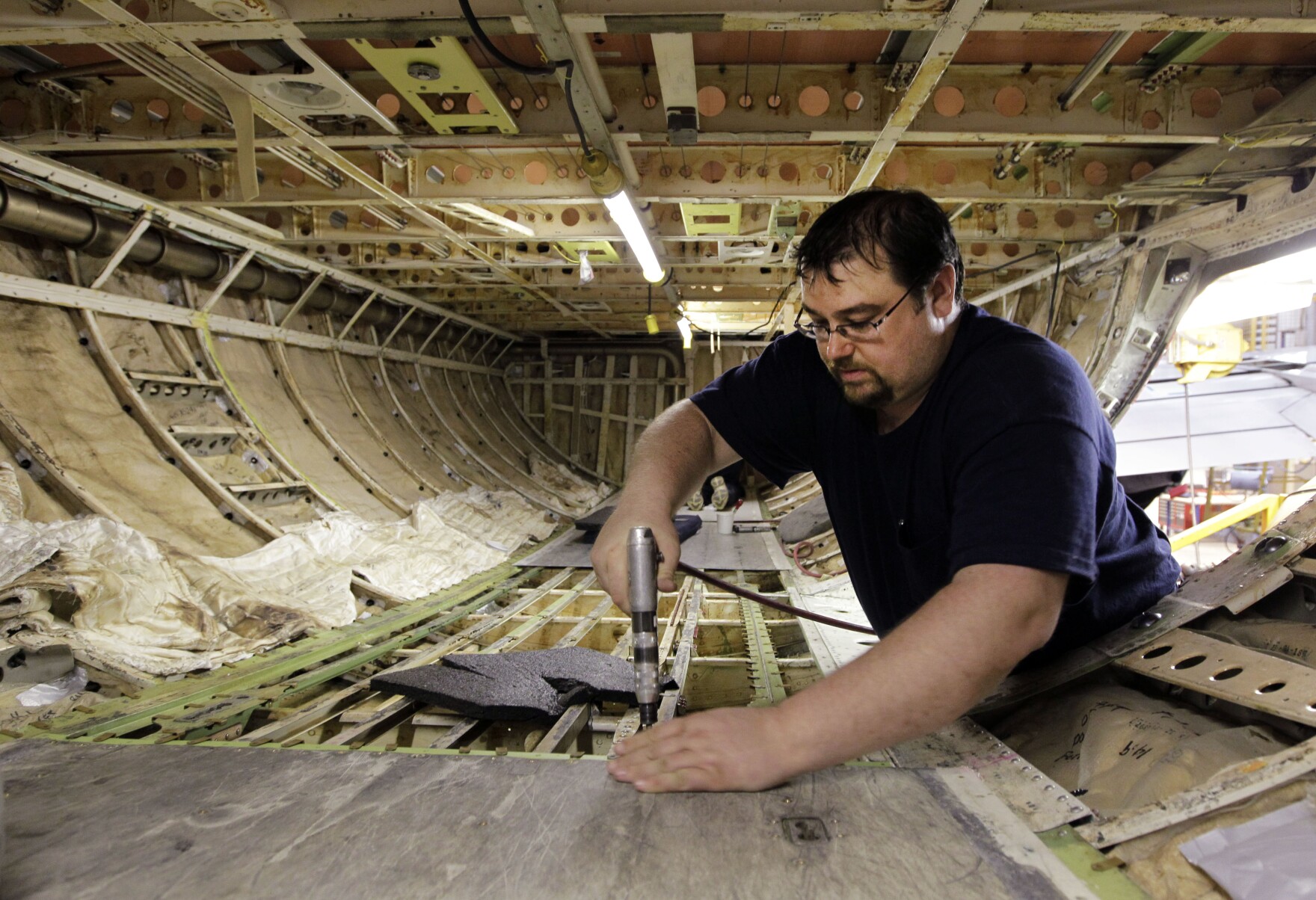 Chris Book performs maintenance work on the floor in the cargo hold of a Boeing 737 at the AAR in Indianapolis.