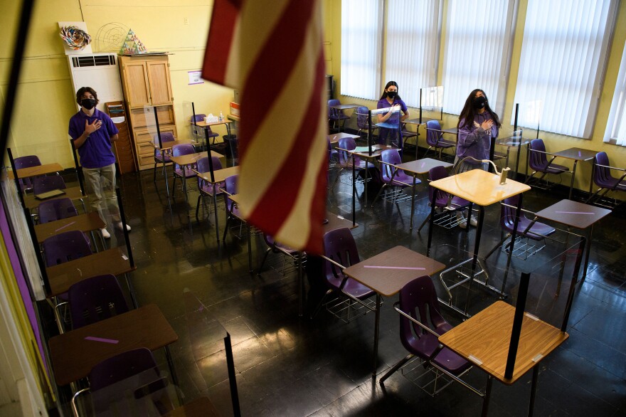 Students stand for the Pledge of Allegiance as they return to in-person learning at St. Anthony Catholic High School in California on March 24. Masks and physical distancing are proving to have some major public health benefits, keeping people from getting all kinds of illnesses, not just COVID-19. But it's unclear whether the strict protocols would be worth the drawbacks in the long run.