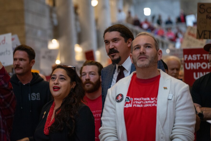Democratic lawmakers, like Rep. Grant Amjad Miller, second to the back and center in a suit and tie, joined the crowd in calling for Gov. Spencer Cox to veto HB267, the bill banning public labor union collective bargaining. The Democratic caucus opposed and voted against it.