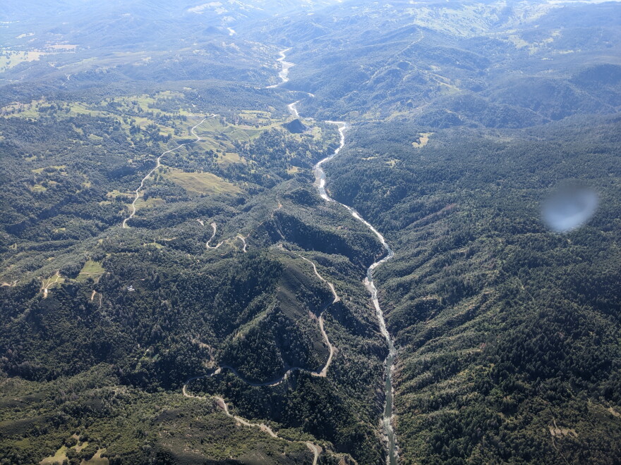 A river running through mountains alongside a road, viewed from above.