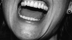 Album cover for July Talk featuring a black and white photo of a person's neck and the lower half of their face. Their mouth is open wide and their teeth and tongue are showing.