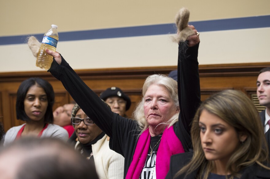 Flint resident Glaydes Williamson holds up a bottle of water from the city and hair pulled from her drain during a House Oversight and Government Reform Committee hearing in Washington, D.C., in February.