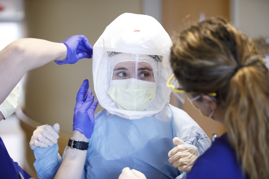 RN Marcia Alverson, left, and Amy Richardson, right, work fitting a Powered air-purifying respirator suit on Bailey Adamson, before she enters a patients room as staff at the Albert B. Chandler Hospital work with Covid-19 patients on April 2, 2020 . Photo by Mark Cornelison | UKphoto