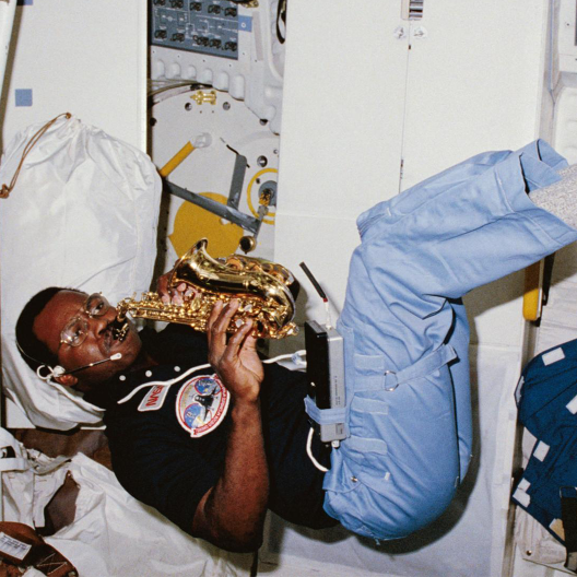 Ronald McNair plays the soprano saxophone while floating in the middeck of the Space Shuttle Challenger during his first flight STS-41B. February 14, 1984.