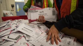 Election worker Kristen Mun from Portland empties ballots from a ballot box at the Multnomah County Elections Division Tuesday, Nov. 3, 3030 in Portland, Ore.