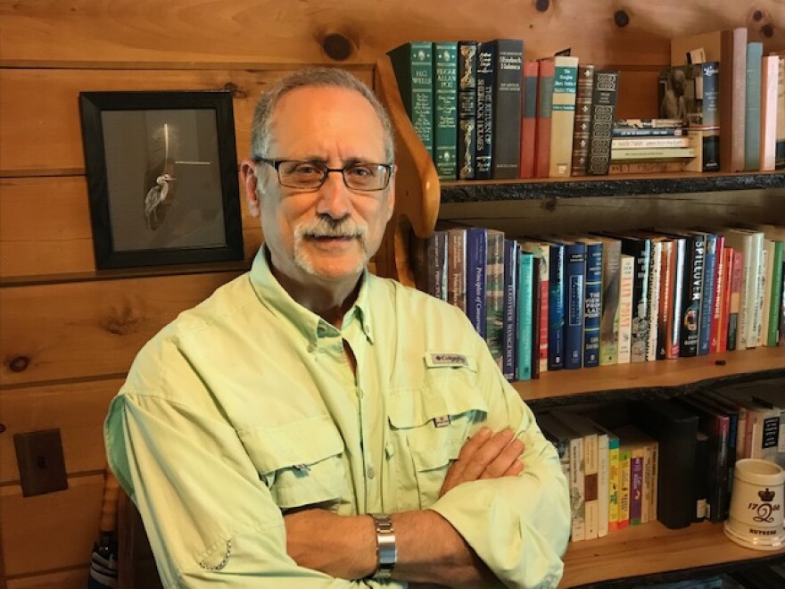 Author Gary Meffe stands with arms folded in front of a bookshelf