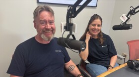 A man and a woman in a Rivian shirt pose for a photo in a radio studio