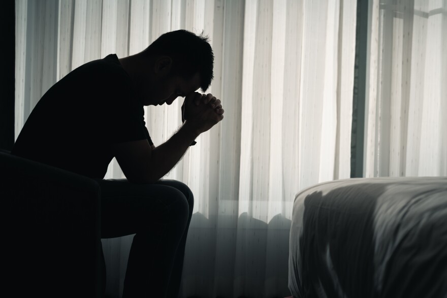 Silhouette depressed man sadly sitting on the bed in the bedroom, depression concept