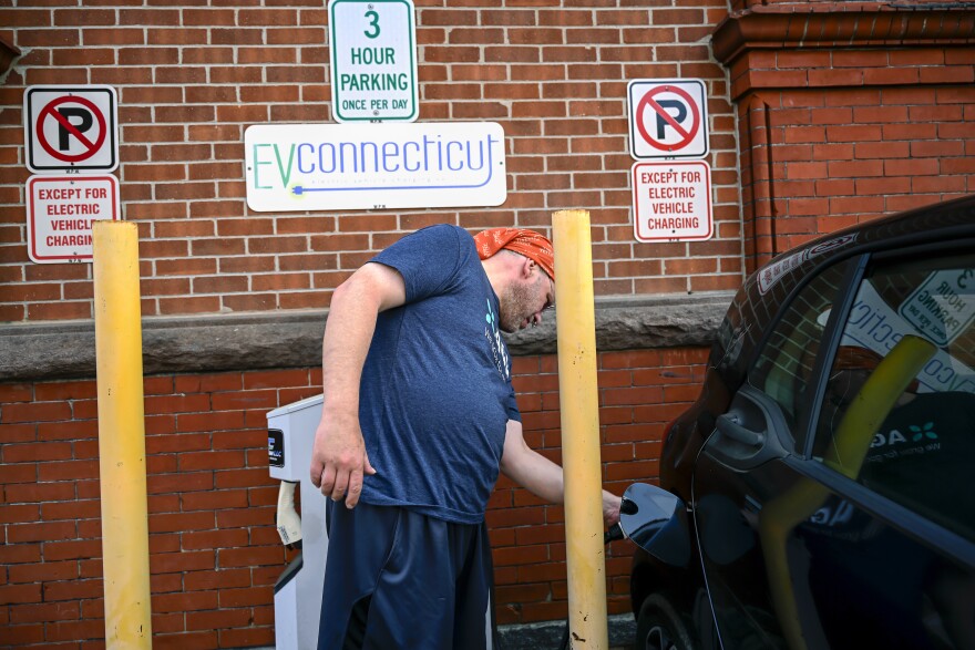 Enos R. Charlen hooks up his car at the free charging stations at the Windham Town Hall in Willmantic, Connecticut May 09, 2023. He lives in Liberty Hill and has had his electric car for over a year, “ I love it! “It gets me where I need to go, he said”