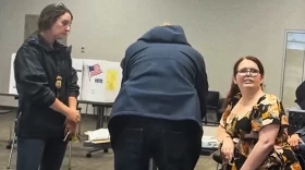 Paigelynne Gonyea, at right, refusing to sign a warning letter delivered by two federal immigration agents as she worked at a polling place in Syracuse, June, 2026.