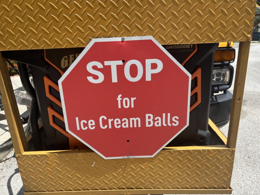 A red octogon sign that says STOP for Ice Cream Balls is hanging on the front of a yellow bus 