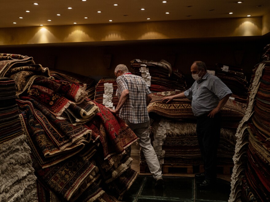 Ferudun Ozgumus (left) walks through a carpet shop above a basement containing Byzantine-era ruins.