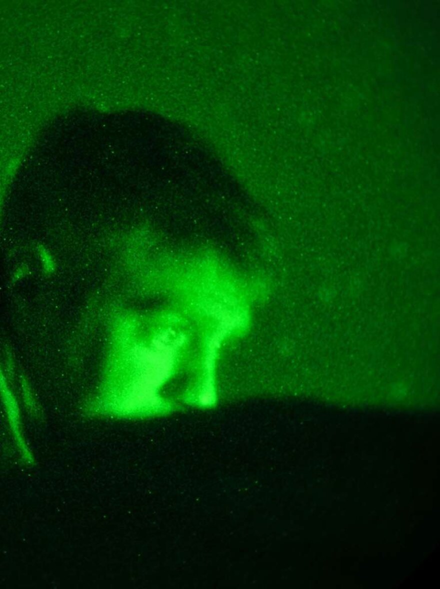 In the middle of the night, Tech. Sgt. John Oliver watches a video monitor and communicates with pilots thousands of feet overhead.