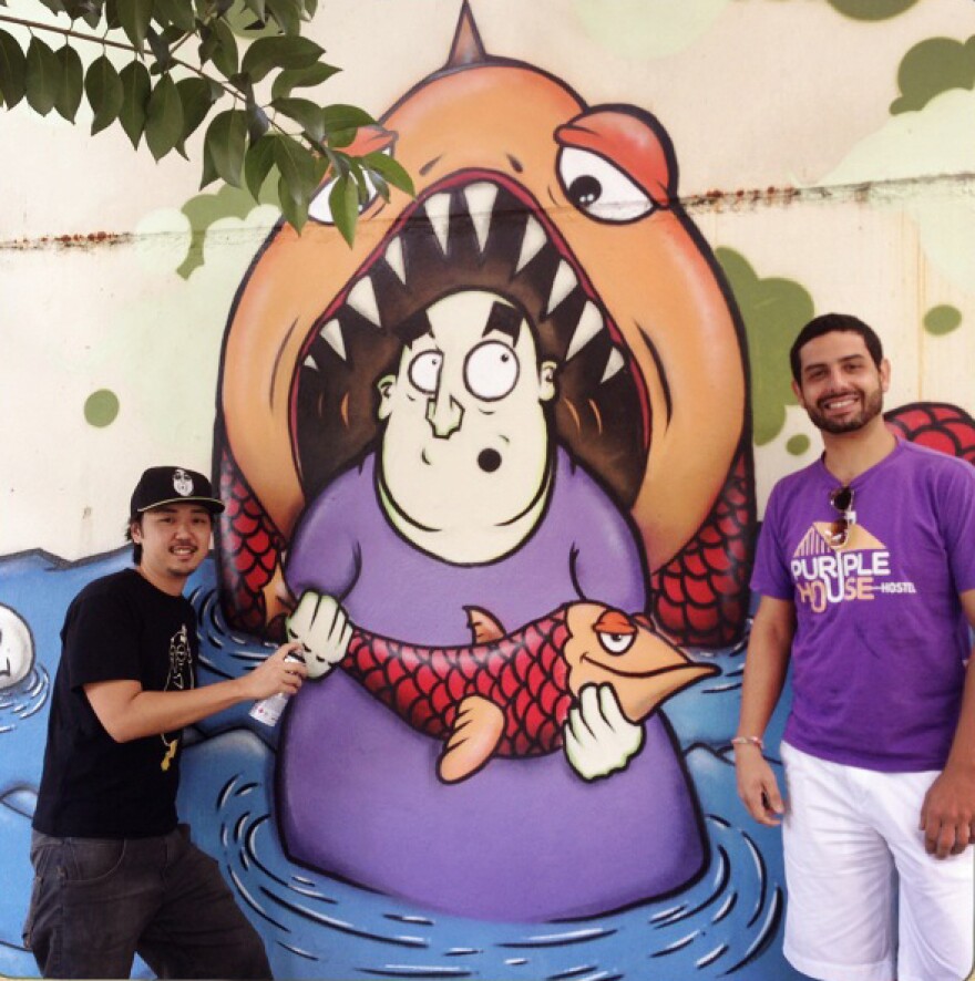 Artist Guilherme Matsumoto (left) painted this mural on the wall of Walter Orsati's Purple House Hostel in Sao Paulo. The two were matched up by the Color+City urban art project.