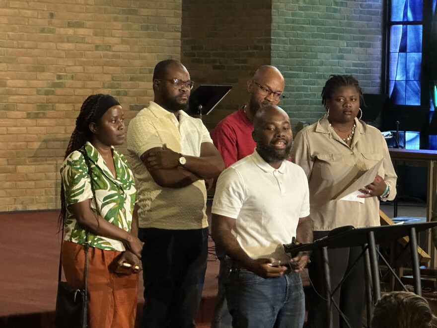 Five Haitians standing around a podium in a church. Haitian members of Organizing Undivided thank the Miami Valley community for publicly supporting Haitian immigrants.