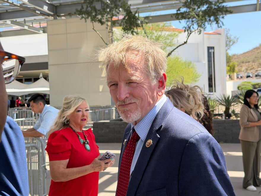 Man with light hair and beard in suit stands outside