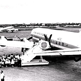 group in BW image gather to get on a Pan Am plane in the 1960s 