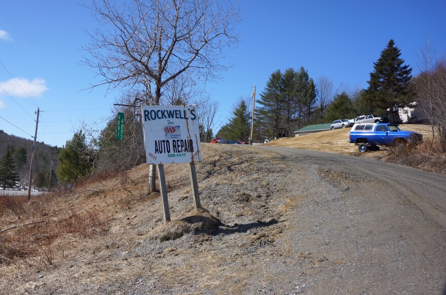 A sign for Rockwell's Auto Repair next to a dirt driveway.