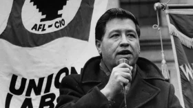 Cesar Chavez with a microphone in hand giving a speech at a rally