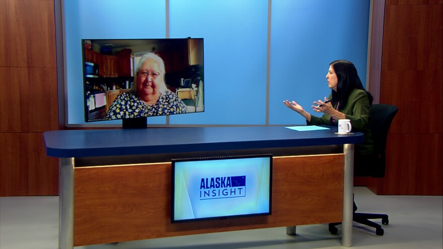 On a TBV set, a woman visible on a screen has a conversation with a woman sitting at a desk in-studio.