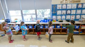 FILE - In this Oct. 6, 2020, file photo, kindergarten students check to make sure they are standing at the proper social distancing space as they line up to go outside during the coronavirus outbreak at the Osborn School, in Rye, N.Y. Schools and camps across the county are making plans to help kids catch up academically this summer after a year or more of remote learning for many of them. (AP Photo/Mary Altaffer, File)