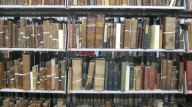 Shelves filled with old, leather-bound books, many tied with white string