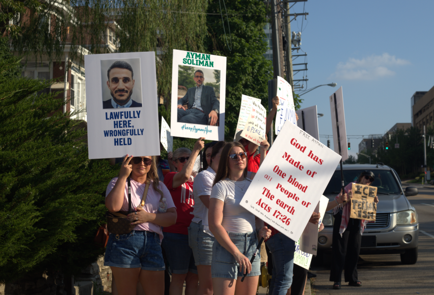A group of people holding signs with messages of support like "Lawfully here, wrongfully held"